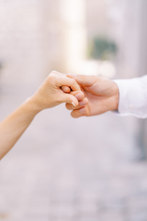 Groom holds bride hand in his own. Cropped. Facelessの写真素材