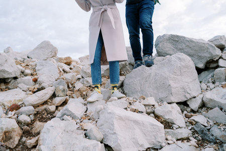 Man and woman are walking along a rocky slope. Cropped. Facelessの写真素材