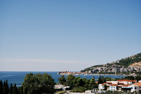 View over the red roofs of houses on the sea coast of Budva at the foot of the green mountains. Montenegroの写真素材