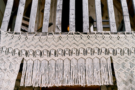 Macrame curtain hangs from a wooden canopy at a house