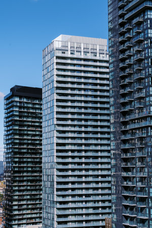 Modern high-rise buildings with glass facades under a clear blue sky, reflecting sunlight.の写真素材