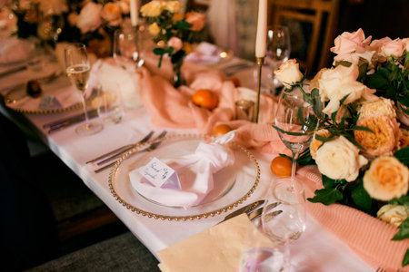 Invitation lies on a napkin on a plate near bouquets of flowers on the festive table