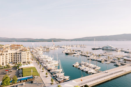 Large marina with rows of yachts moored off the shore with expensive hotels. Porto, Montenegro. Droneの写真素材