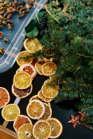 Dried pieces of orange, coniferous branches and acorns for a Christmas wreath lie on the tableの写真素材