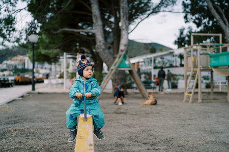 Little girl sits on a swing-balancer and looks awayの写真素材