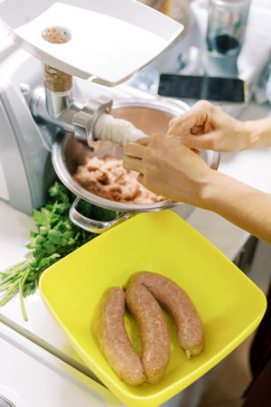 Person using an electric meat grinder to make sausage.