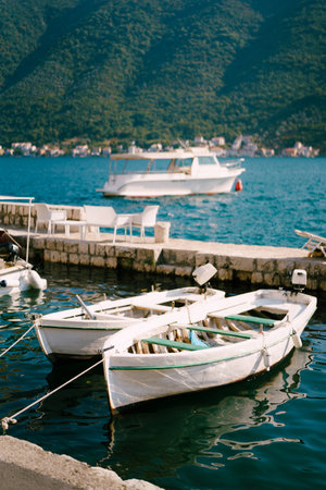 Fishing boats are moored to the shore between two piers