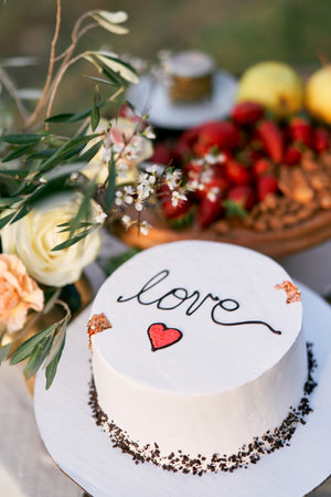 Wedding cake is on the table next to the bouquet of flowers. Caption: Loveの写真素材