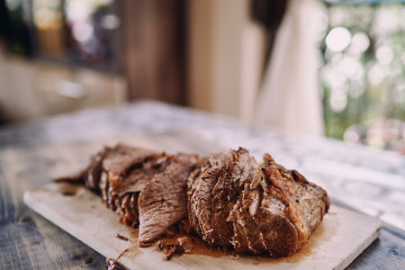 Pieces of roast beef lie in a row on a cutting board on the kitchen table