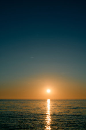 Sparkling path from the rays of the orange sunset sun on the seaの写真素材