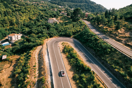 White convertible is driving along a serpentine road in the mountains. Droneの写真素材