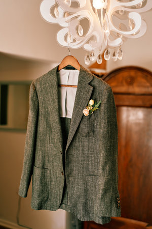 Groom gray jacket hangs on a chandelier in a hotel roomの写真素材