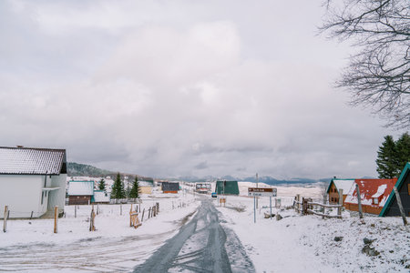 Highway through a snow-covered village with colorful houses in a mountain valleyの写真素材