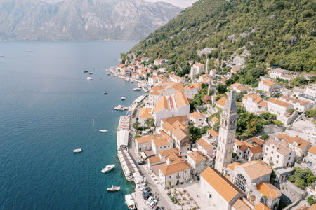 Moored boats off the coast of Perast with the high bell tower of the Church of St. Nicholas among ancient houses. Montenegro. Droneの写真素材