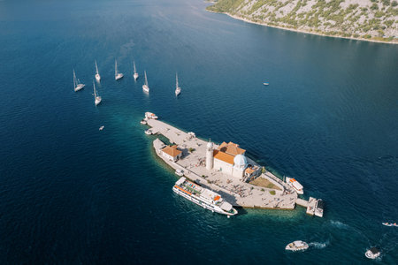 Church of Our Lady of the Rocks on an island in the Bay of Kotor surrounded by moored boats and a...