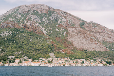 View from the sea of the ancient town of Perast at the foot of a high wooded mountain. Montenegroの写真素材