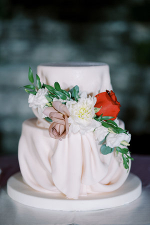 Wedding cake decorated with flowers stands on the tableの写真素材