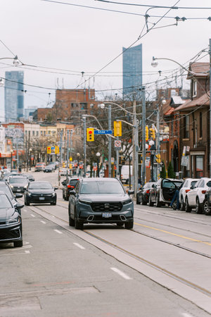 Toronto, Canada - April 17, 2026: Sleek black automobile glides along Toronto avenue surrounded by stationary cars