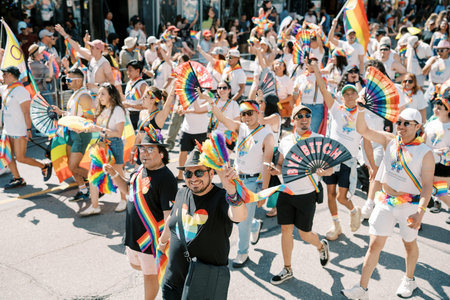 Toronto, Canada - June 29, 2025: Allies dancing with rainbow folding fans