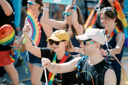 Toronto, Canada - June 29, 2025: Friends smiling and waving rainbow fans