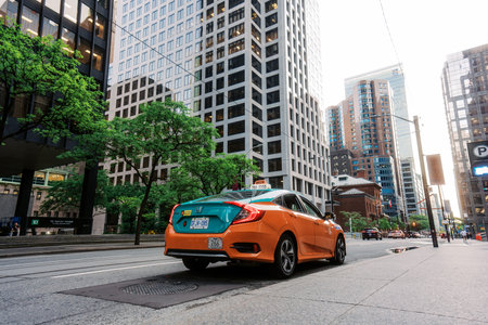 Toronto, Canada - June 20, 2026: Orange and teal Beck taxi on downtown street with modern high-rise buildings