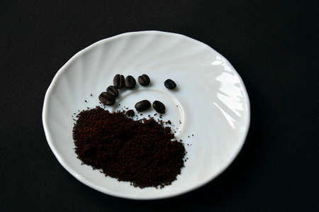 Coffee beans and ground on a white saucer.の写真素材