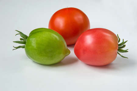 Three tomatoes on a light background. The red and green.の写真素材
