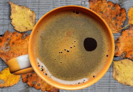 Coffee mug on wooden background. With the autumn leaves.の写真素材