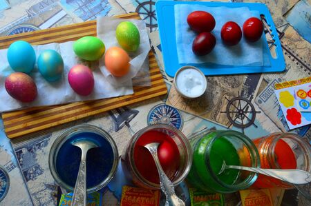 Preparation for the Easter holiday. Coloring chicken eggs in different colors in glass jars with...