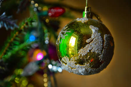 Christmas tree decoration for the New year. A green glass ball on a string hangs on a Christmas tree branch.の写真素材