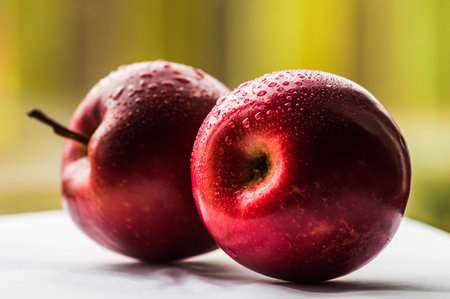Ripe red apples with water drops on a white wooden table.の写真素材