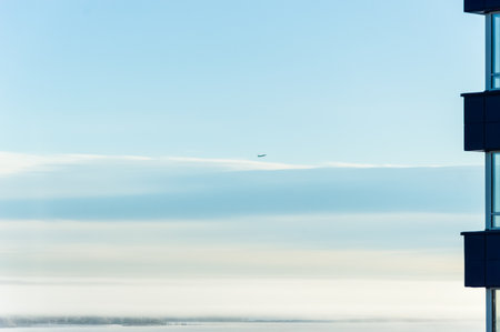 Aerial view of a plane flying over a skyscraper in the fog
