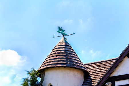 conical slat roof with charming patinated brass vane and blue sky with cloudsの写真素材