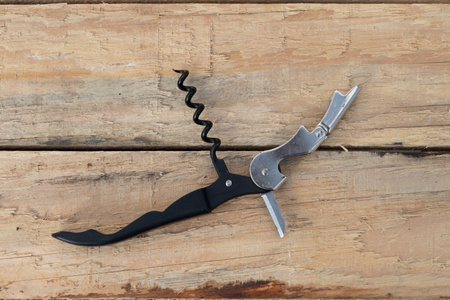 Opened sommelier's knife with corkscrew and bottle opener, waiter's knife professional on a wooden...
