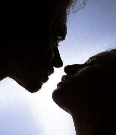 portrait of a romantic couple kissing when illuminated from a window or door.の写真素材