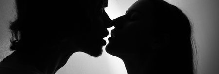 portrait of a romantic couple kissing when illuminated from a window or door.の写真素材