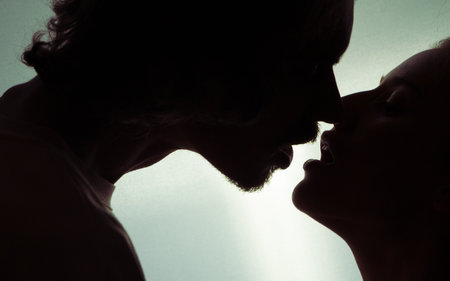 portrait of a romantic couple kissing when illuminated from a window or door.の写真素材