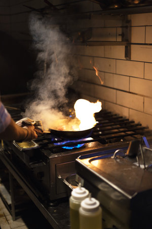 the chef prepares food in a frying pan. strong fire. professional kitchenの写真素材