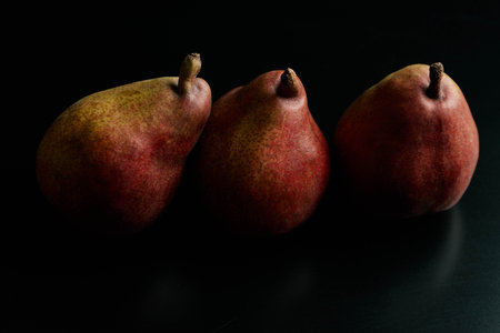 three red pears on a black tableの写真素材