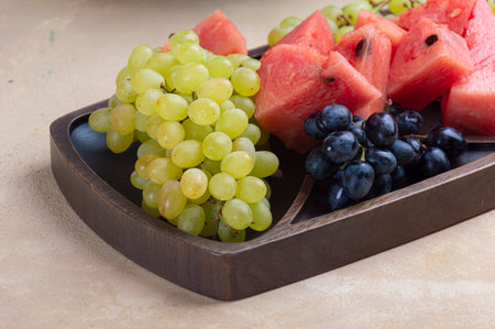 Table with different fruits. Watermelon, grapes on clay plate. Summer fruits on green mint wooden table. Bright fruits on wood board. Autumn fruits: watermelon, grapesの写真素材