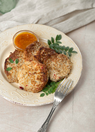 Fish cutlets with sauce and herbs on tablecloths with green salad
