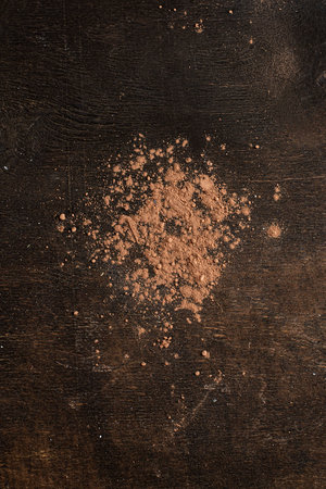 Broken pieces of chocolate and cocoa powder on a dark wooden background.の写真素材