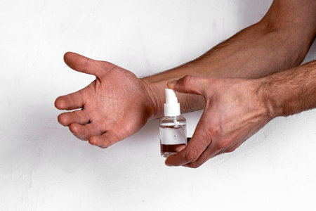 Hand antiseptic treatment. Hands hold a bottle of disinfectant spray. Protection against coronavirus Covid-19. Hands in the cleaning process with a medical disinfectant liquid, on an isolated white background, close-up. Antisepticの写真素材
