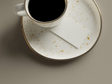 Cup of coffee with a blank business card on a beige backgroundの写真素材