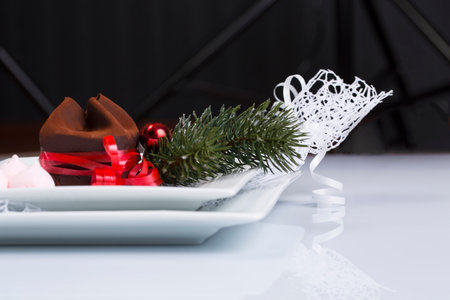 Chocolate dessert on a white plate with a Christmas tree and red ballsの写真素材