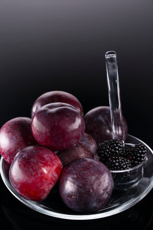 Plums and blackberries in transparent dipper to the Christmas tableの写真素材