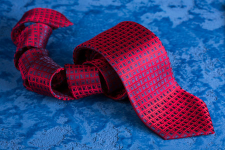 Red tie with a blue pattern on a blue backgroundの写真素材
