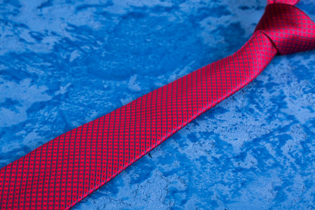 Red tie with a blue pattern on a blue backgroundの写真素材