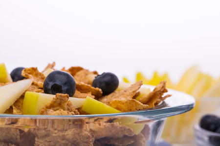 Muesli with apples and blueberries, milk carafe on a white background