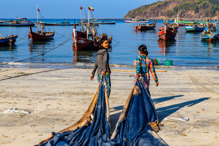 NGAPALI, MYANMAR - FEBRUARY 10, 2020 : Fisherman village. Women working at drying fish. Low income life, down to earth.のeditorial素材